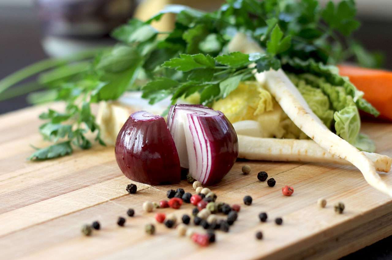 Fresh herbs and vegetables on a wooden cutting board with spices